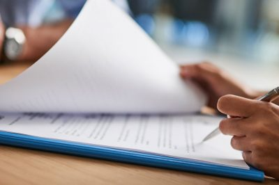 Person signing an investment agreement with pen and paper