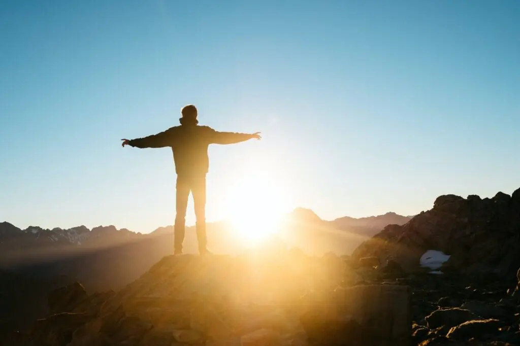 Man standing in freedom on a mountain peak, contemplating the question 'Is fire for you?'