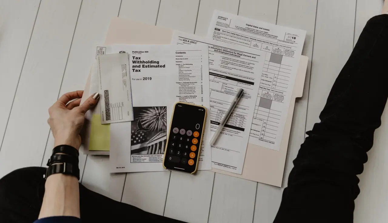 Person doing tax preparation with documents and calculator.