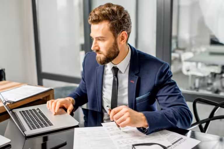 Businessman working on laptop in office managing finances with Tanti Financial Services accounting and advisory support.