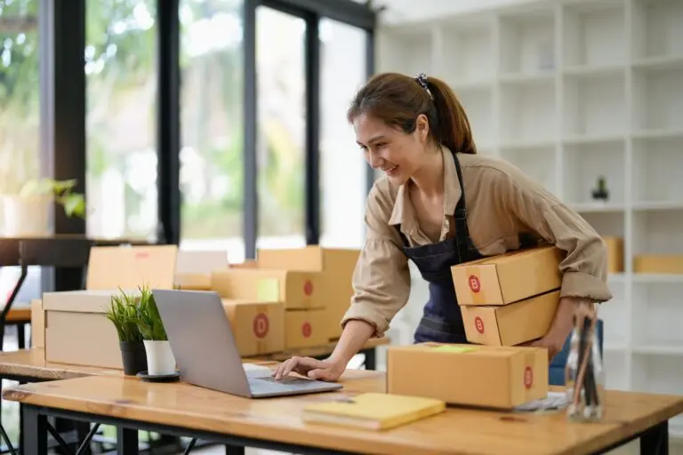 Woman managing online business with packages and laptop.