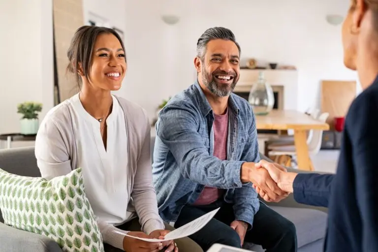 Couple meeting with advisor, shaking hands and smiling.