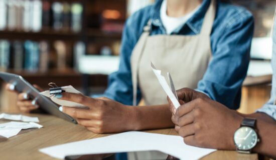 Café workers handling receipts and a tablet