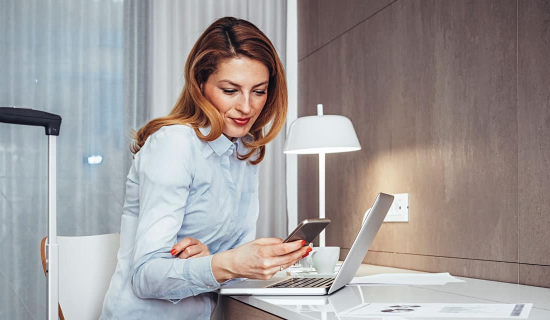 A confident woman utilizing her phone, illustrating the peace of mind offered by Corporate Travel Insurance.