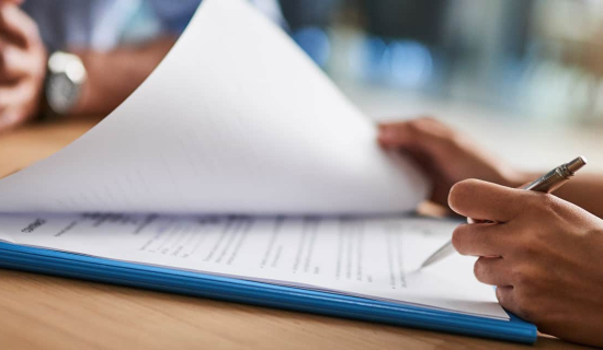 A person signing a paper for Professional Indemnity Insurance.